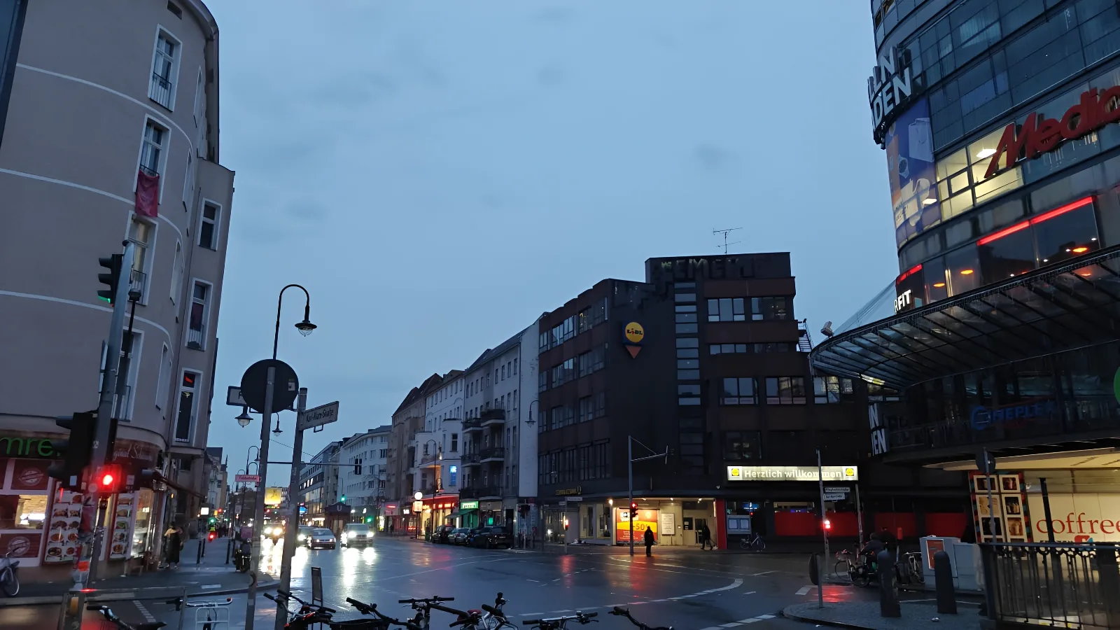 A city street at dusk with shopfronts lit up