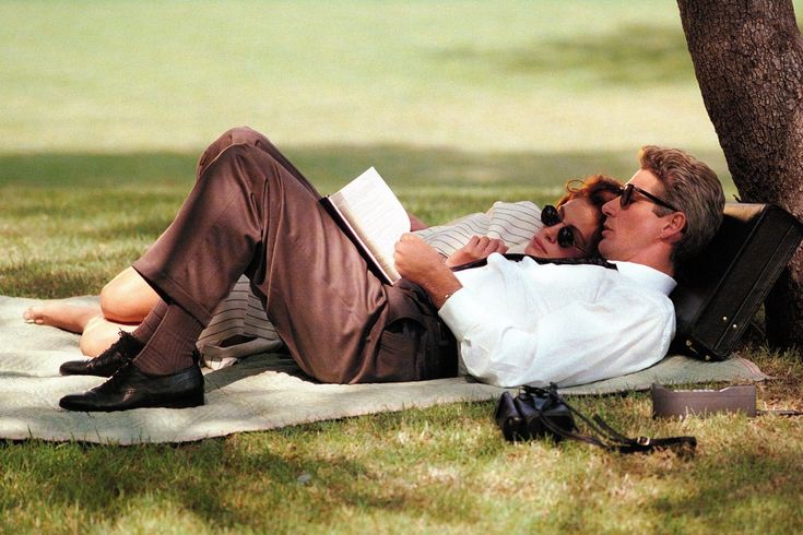 A couple reading and resting together under a tree