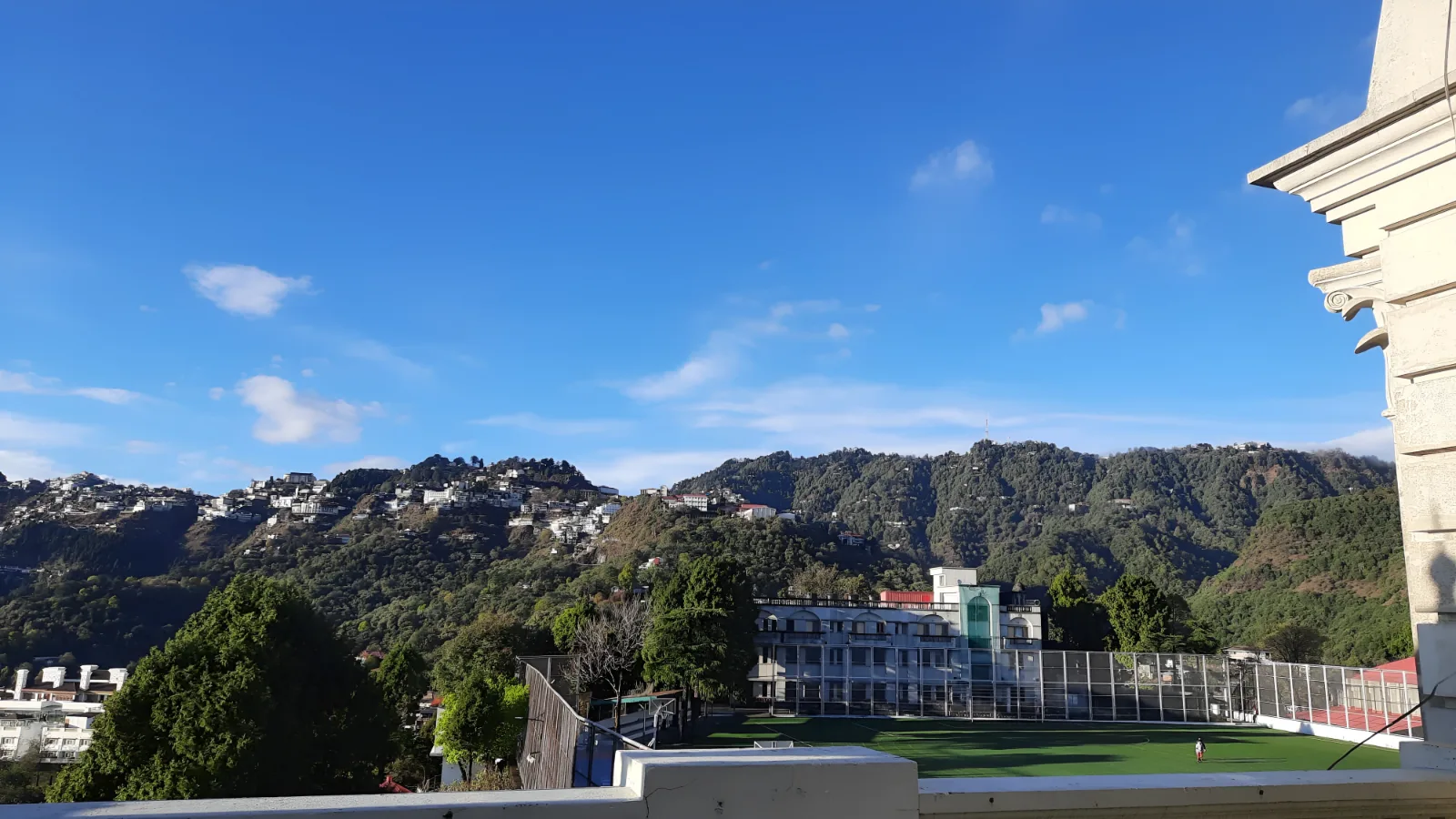 A view of green mountains and a hillside town from a terrace