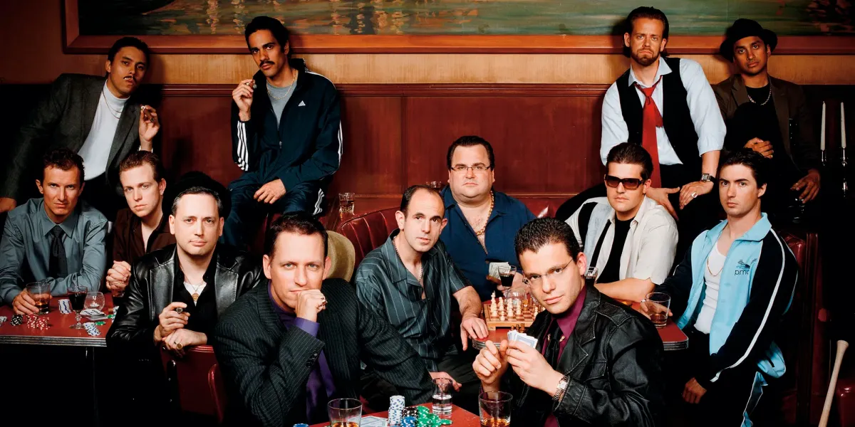 A group portrait around a poker table in a red-lit lounge
